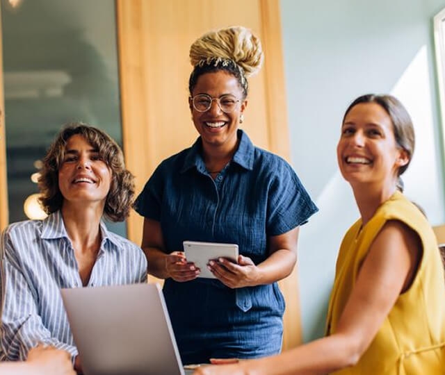 Três mulheres sorrindo no escritório