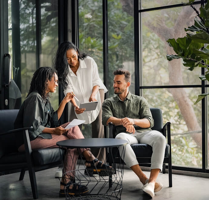 Três pessoas sorrindo, duas mulheres e um homem, segurando um tablet